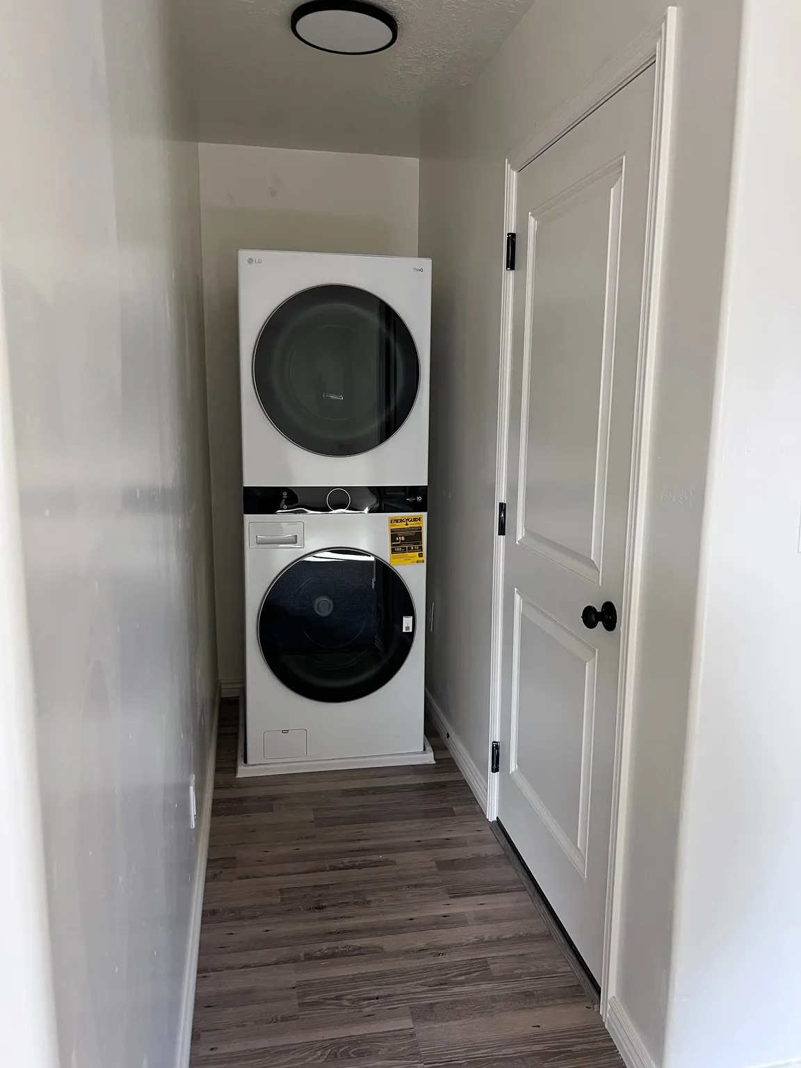 Laundry room featuring stacked washer and clothes dryer and dark wood-style floors
