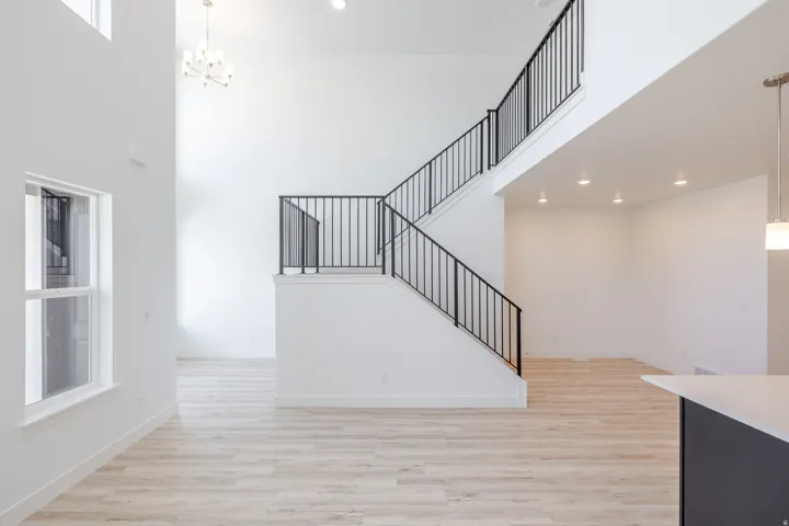 Two-story entry with an open staircase, black metal railings, and a contemporary chandelier