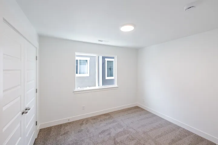 Interior space featuring a window with white trim, gray carpet, and a flush-mount ceiling light