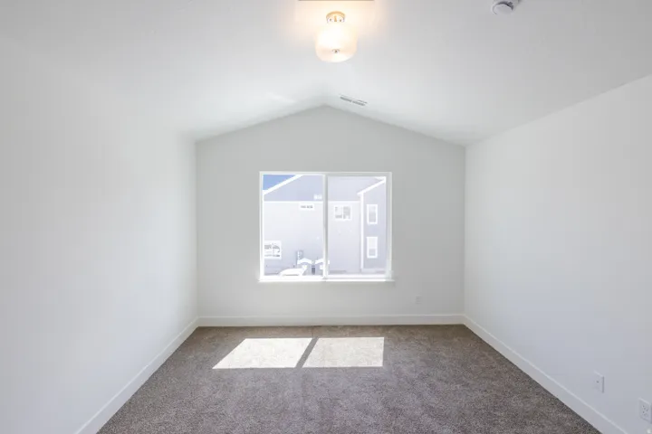 Vaulted ceiling, recessed window, wall-to-wall carpeting, and overhead lighting fixture