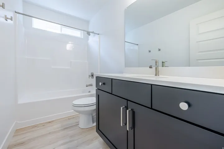 Modern bathroom featuring a dark vanity with a white countertop, undermount sink, and brushed nickel faucet