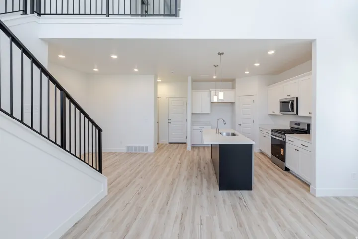 Open-concept living area with wood-finish flooring, a two-story ceiling, and a modern kitchen