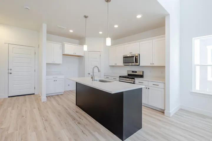 Open-concept kitchen featuring a center island, white cabinetry, stainless steel appliances, and wood-finish flooring