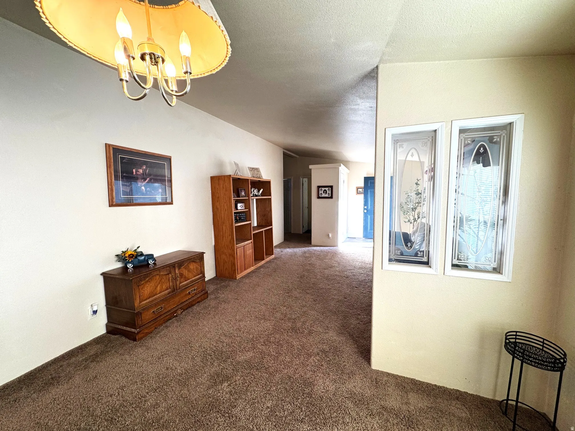 Corridor with dark colored carpet and a chandelier