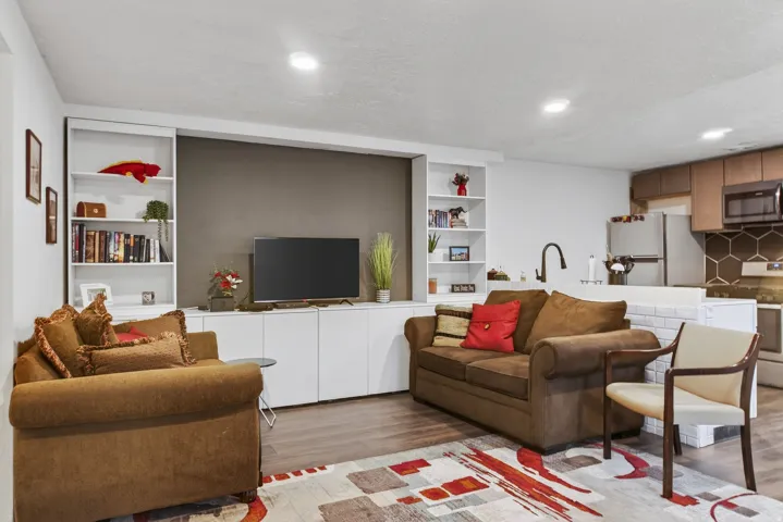 Living room with light wood-style flooring, built in features, recessed lighting, and a textured ceiling