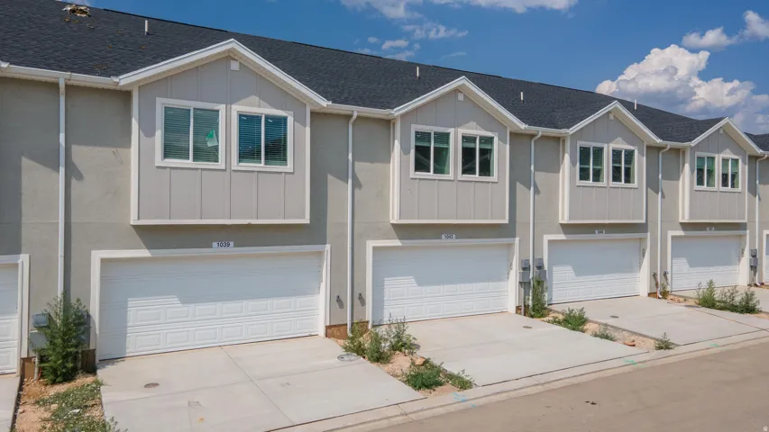 View of front of home featuring a shingled roof, board and batten siding, a garage, and driveway