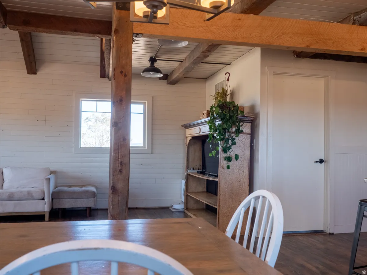 Dining area featuring dark wood-style floors, wooden walls, and a wood ceiling with exposed beams