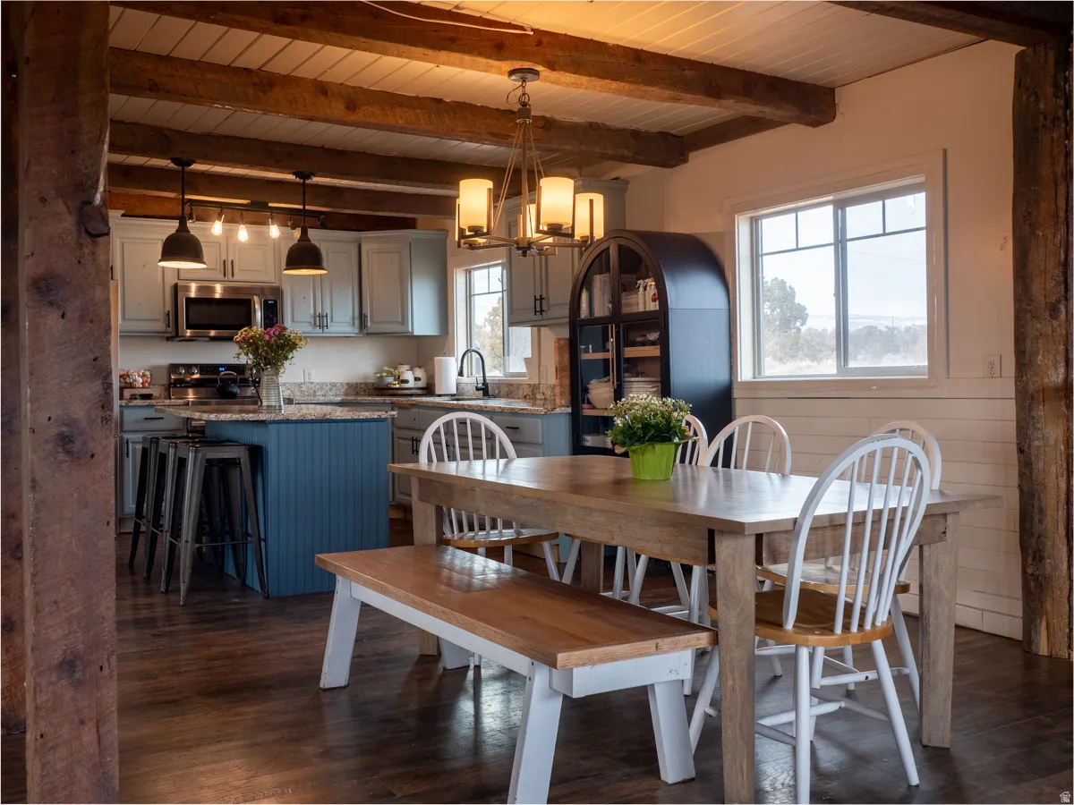 Dining room featuring dark wood-style floors, a chandelier, and a wood ceiling with exposed beams