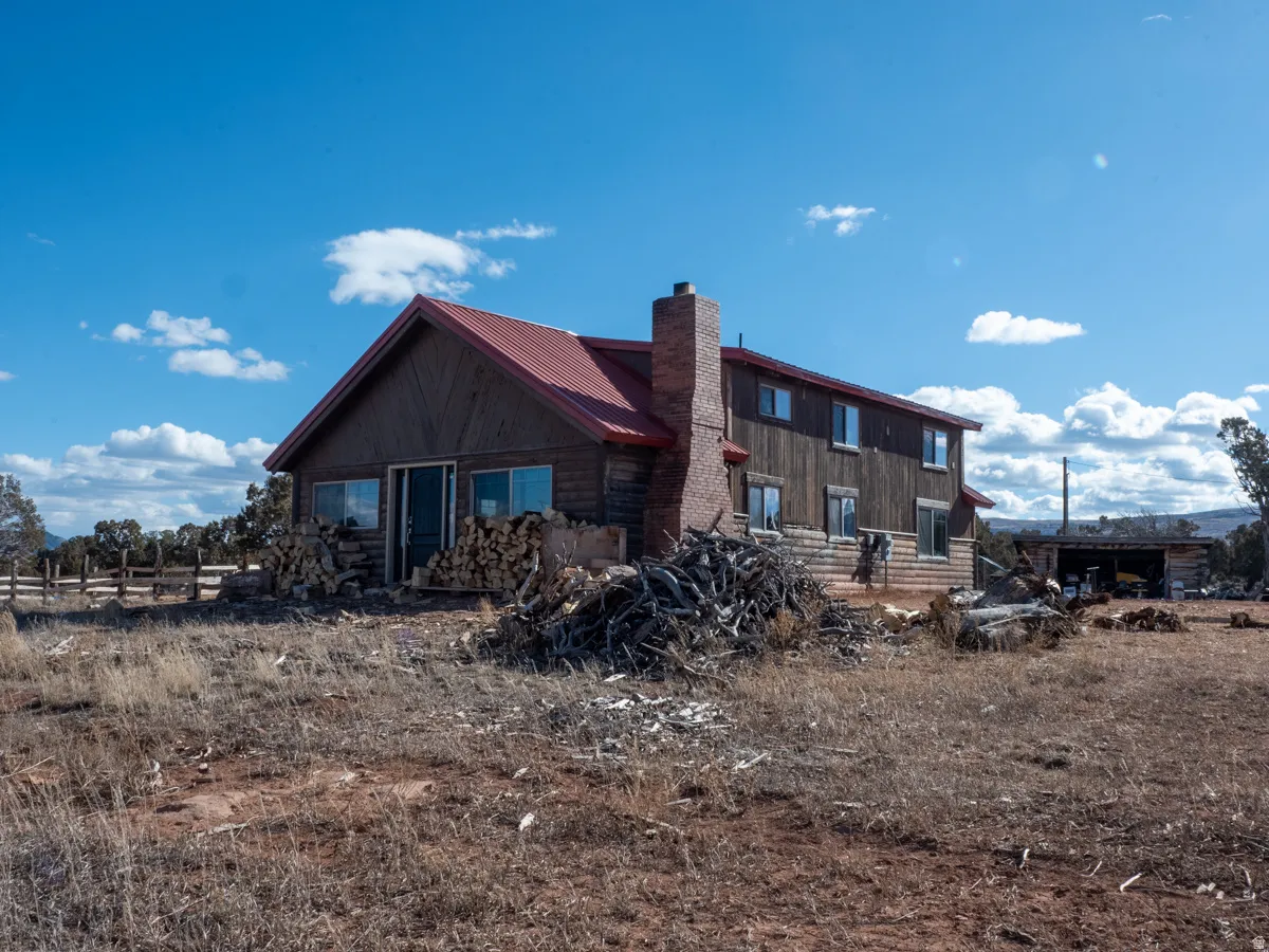 Rear view of house featuring a metal roof and a chimney