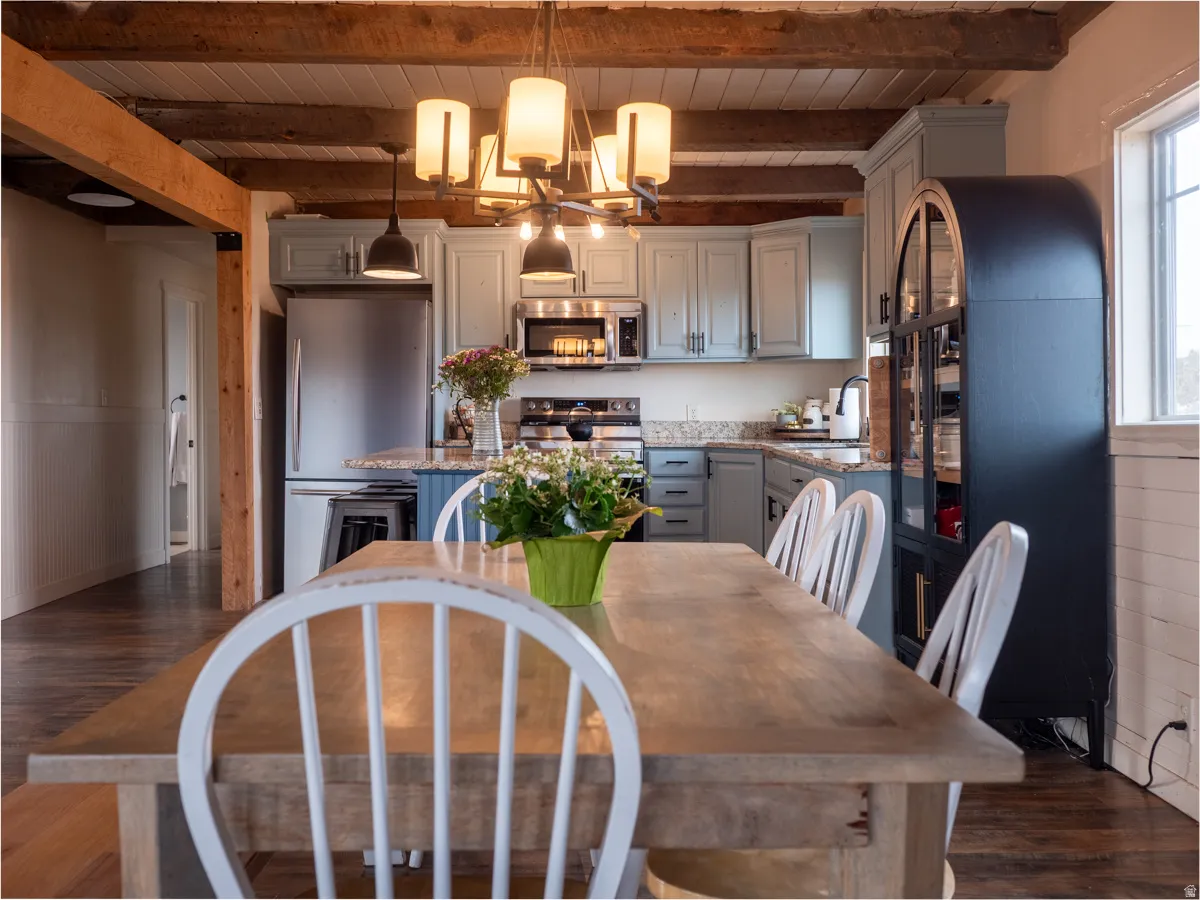 Dining area with dark wood finished floors, a wooden ceiling with exposed beams, and a chandelier