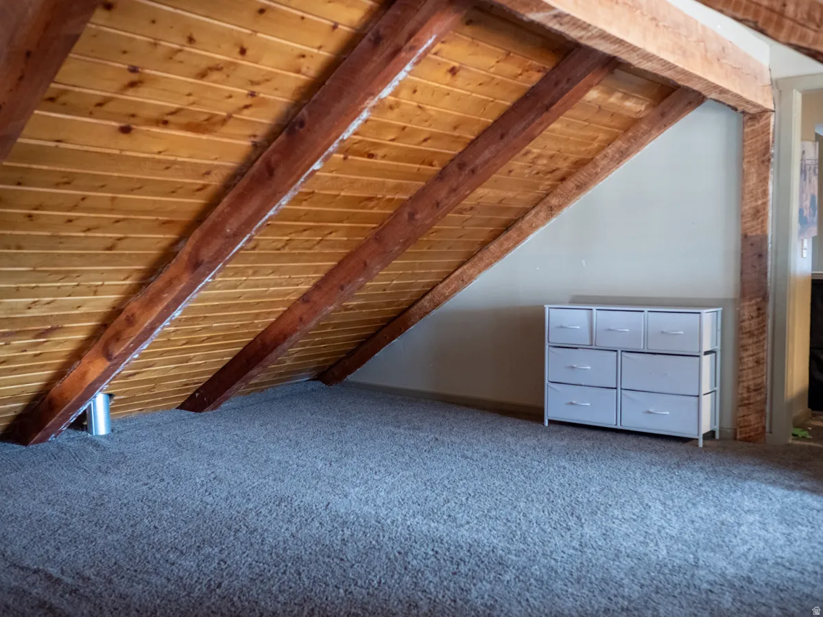 Additional living space featuring wood ceiling, vaulted ceiling with beams, and carpet flooring