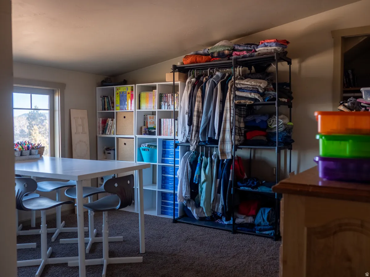 Walk in closet featuring vaulted ceiling and dark colored carpet
