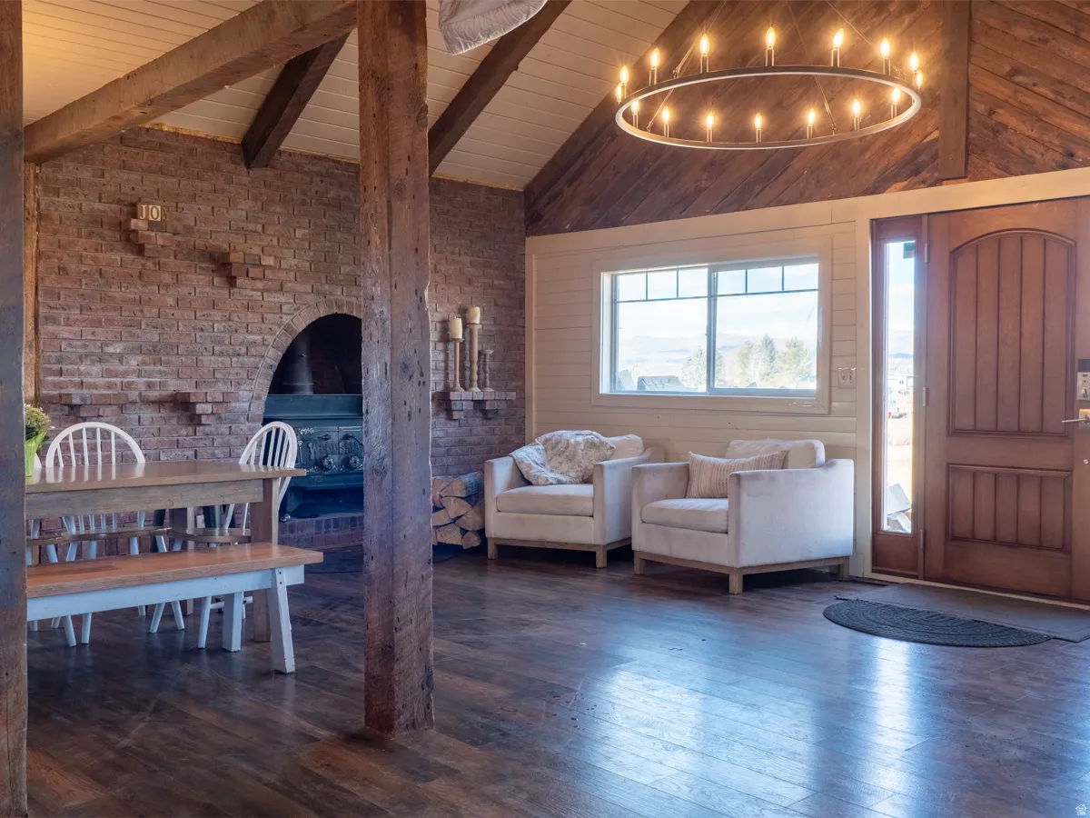 Foyer with brick wall, dark wood-type flooring, lofted ceiling with beams, and wooden ceiling