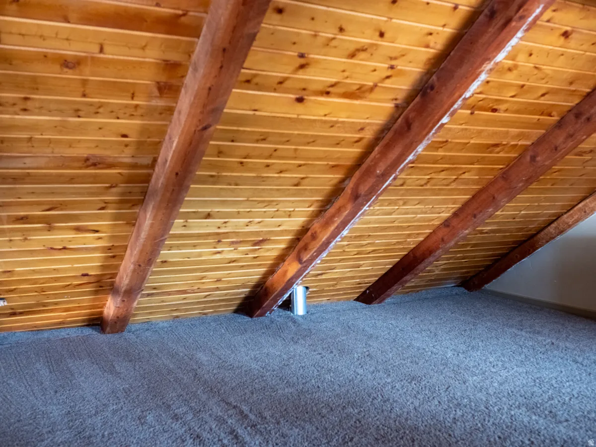 Detailed view of a wooden ceiling with exposed beams and carpet