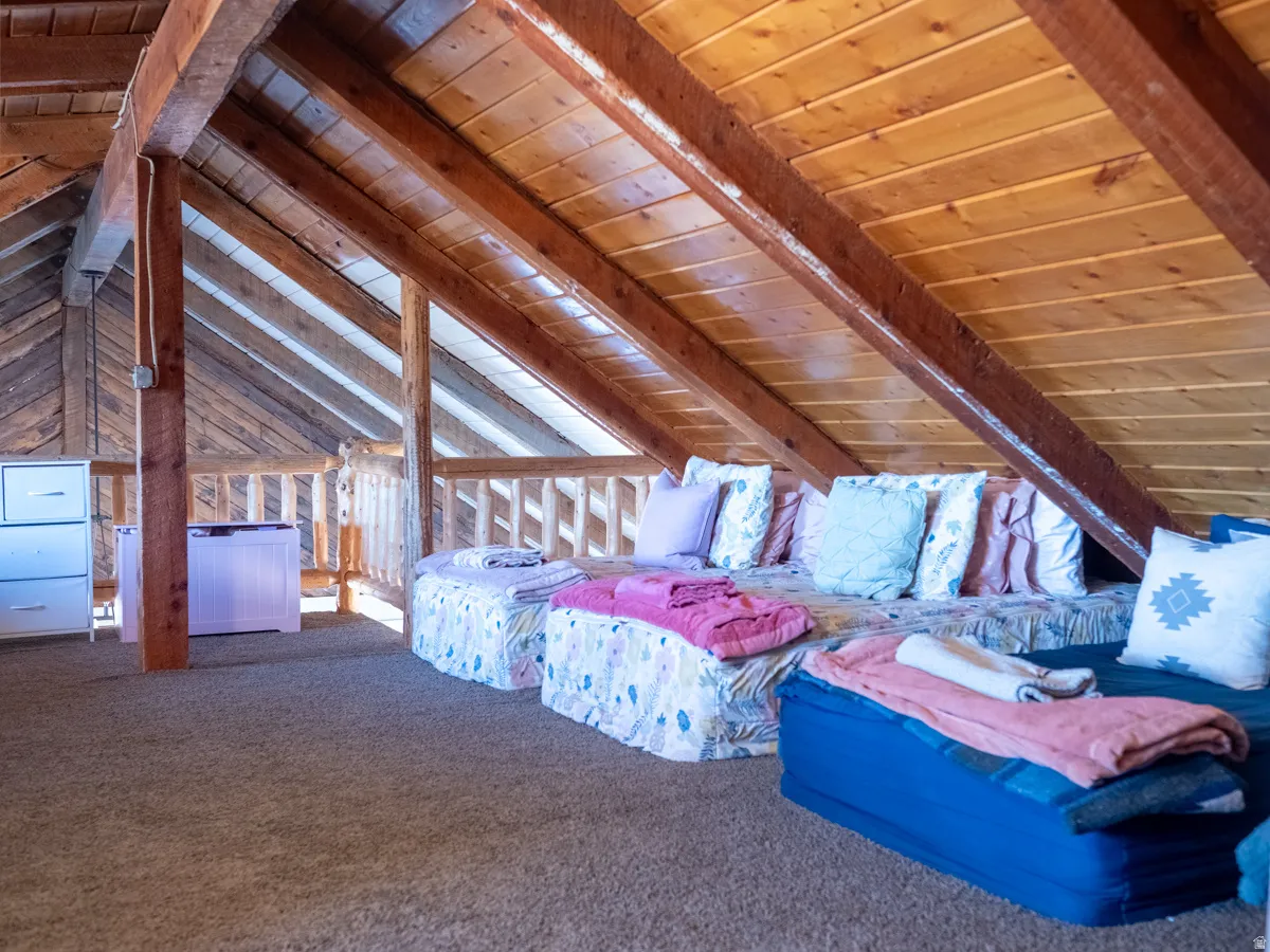 Bedroom featuring wood ceiling, carpet flooring, and vaulted ceiling with beams