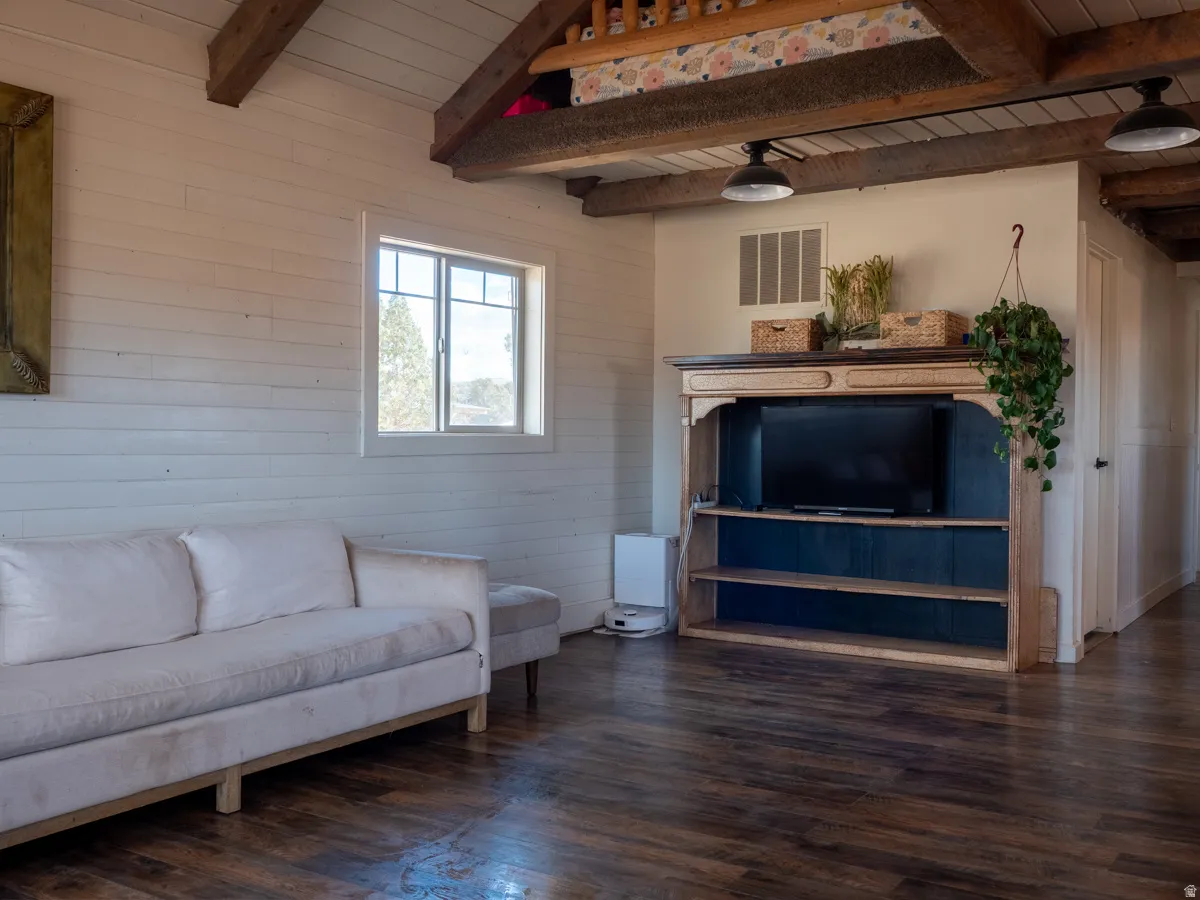 Living room with dark wood-style floors, a wooden ceiling with exposed beams, and wooden walls