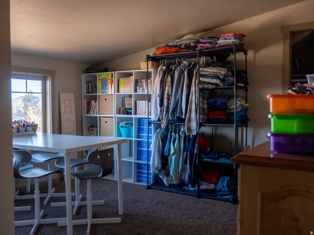 Walk in closet featuring vaulted ceiling and dark colored carpet