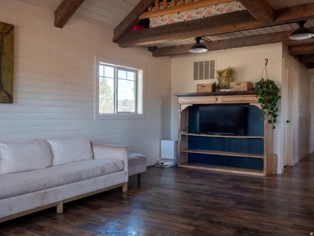 Living room with dark wood-style floors, a wooden ceiling with exposed beams, and wooden walls