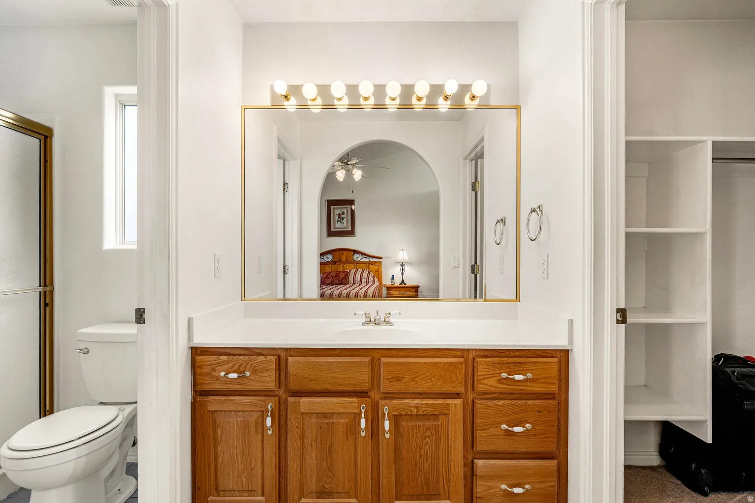 Primary bath featuring vanity, connected bathroom, a ceiling fan, and a spacious closet