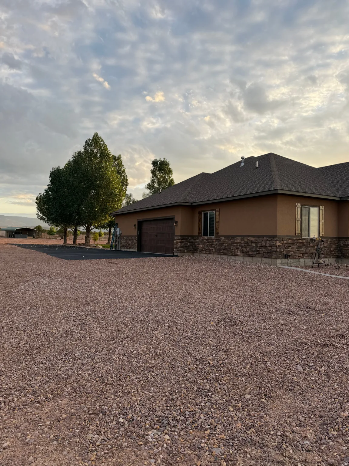 Exterior facade featuring stucco siding, stone veneer accents, and a dark shingle roof
