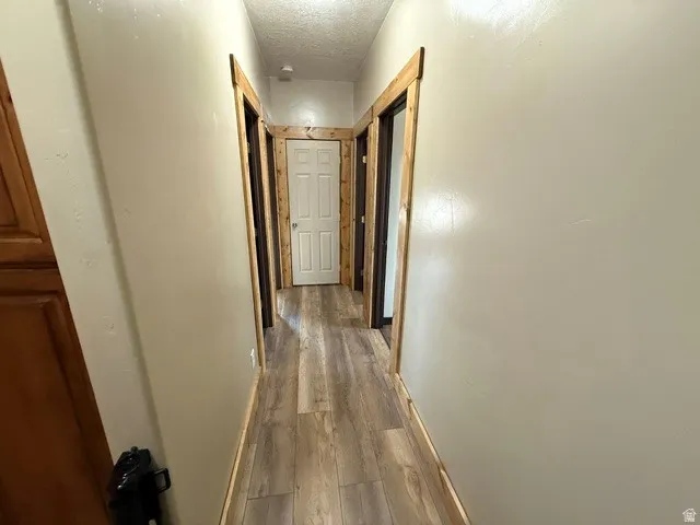 Hallway with a textured ceiling and dark wood-type flooring