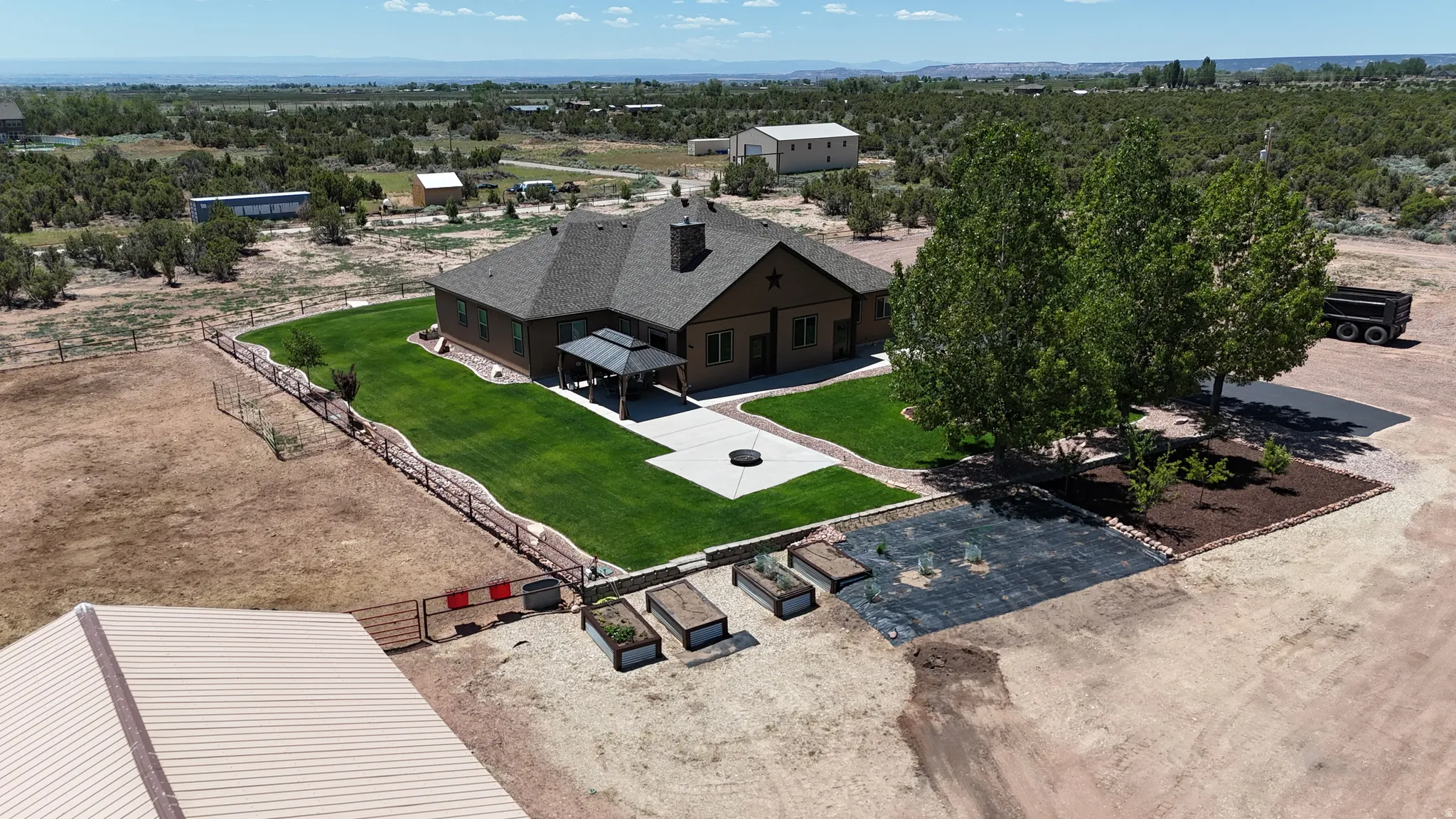 Expansive property featuring a brown-toned residence with a dark shingle roof, an attached covered patio, and a manicured green lawn