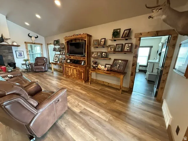Living room with recessed lighting, light wood-style floors, lofted ceiling, plenty of natural light, and a fireplace