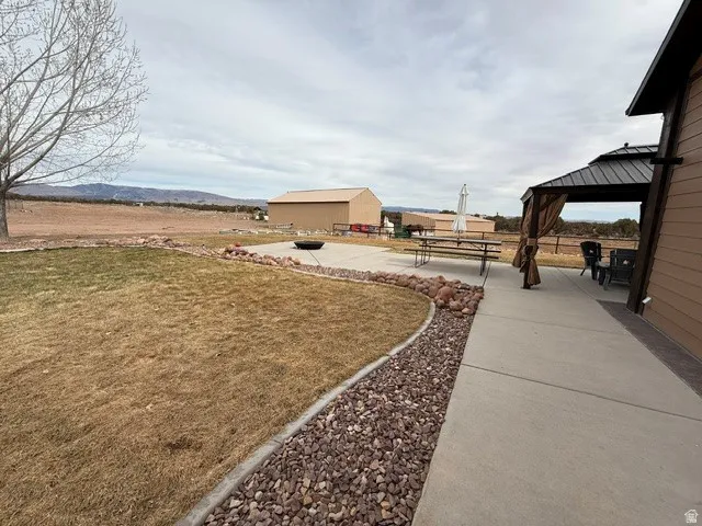 View of grassy yard featuring a patio area, an outdoor structure, and a gazebo