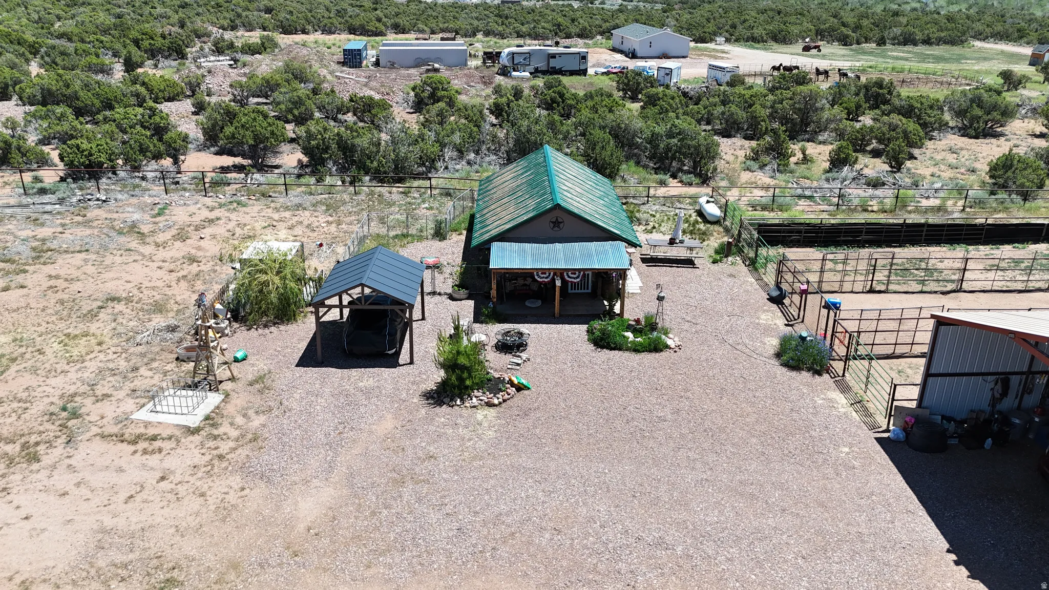 Expansive gravel lot featuring a main structure with a green metal roof and covered porch