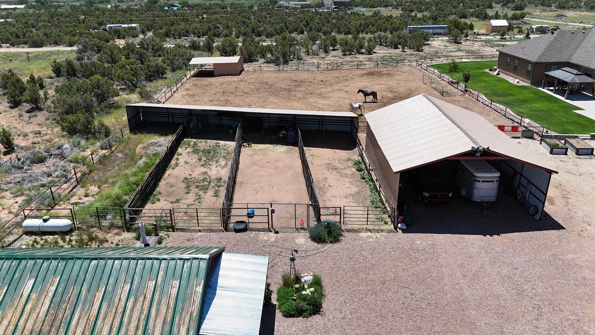 Expansive equestrian facilities featuring a large covered shelter, multiple fenced paddocks, and an additional small outbuilding