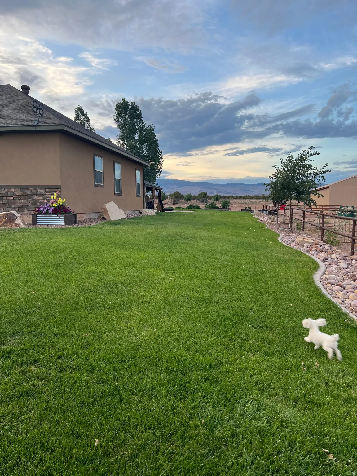 Expansive green lawn bordering a stucco and stone veneer exterior