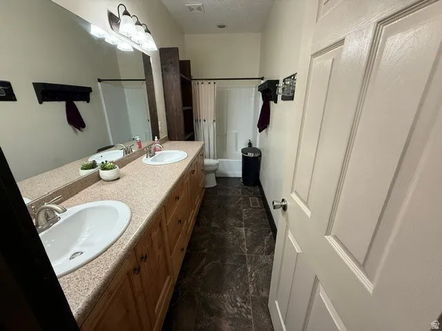 Bathroom featuring double vanity and shower / bath combo