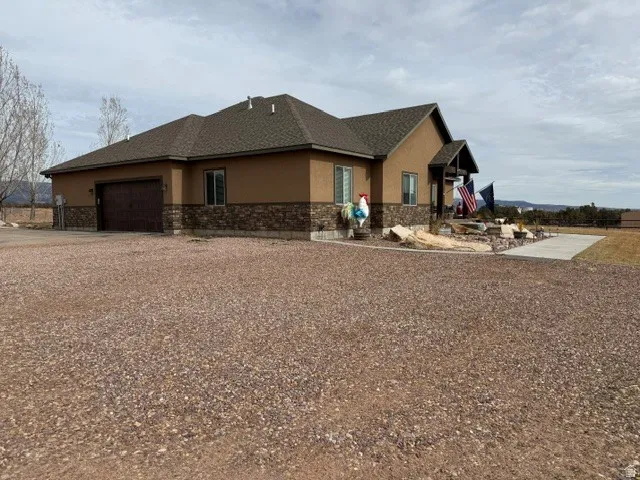 View of home's exterior featuring stucco siding, a garage, stone siding, and driveway