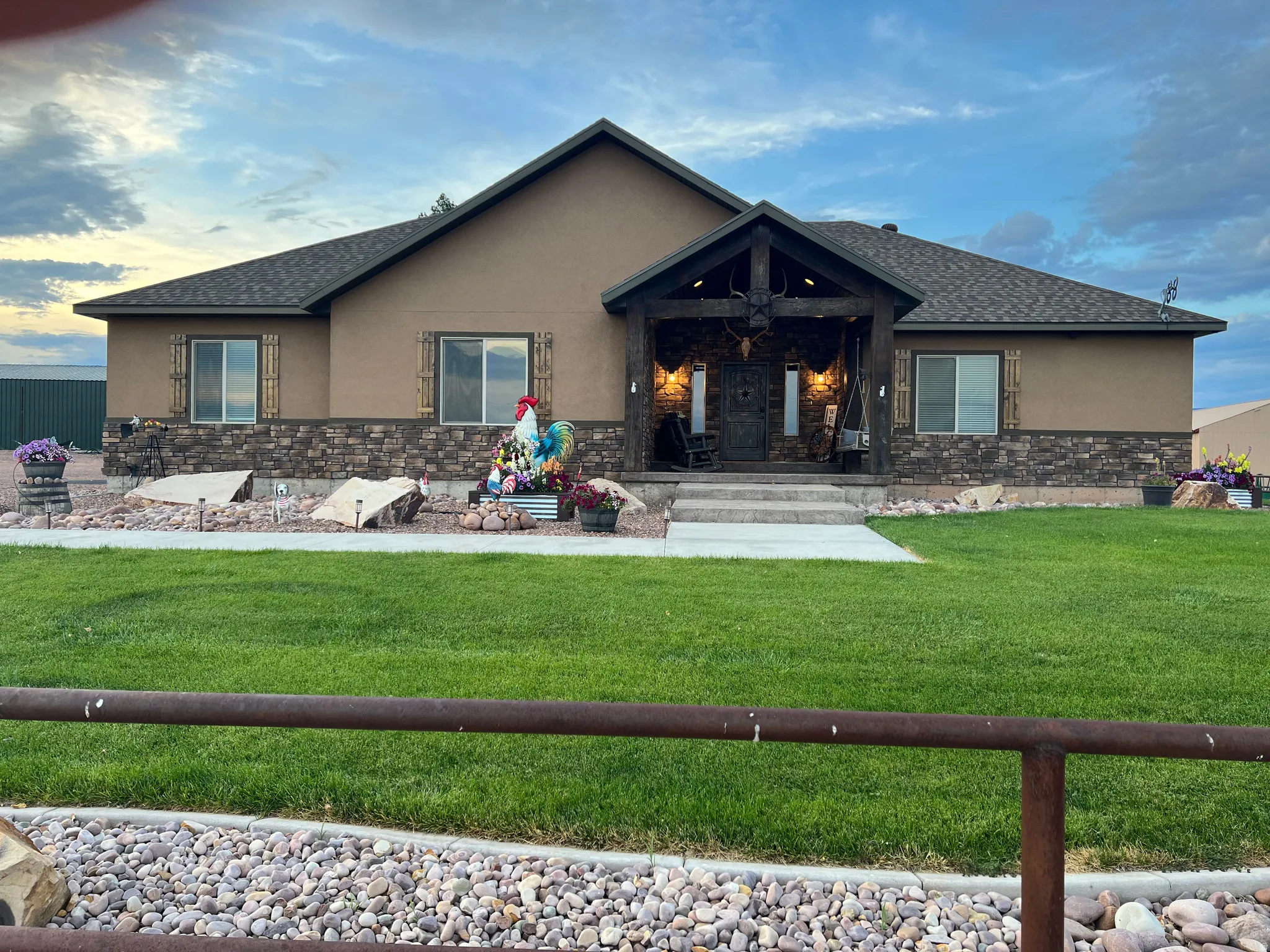 Exterior featuring a covered entry porch with exposed wood beams, stone veneer accents, stucco siding, and a gabled roofline