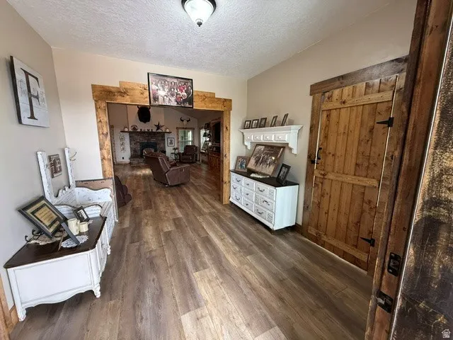 Sitting room featuring dark wood-type flooring, a textured ceiling, and a fireplace with raised hearth