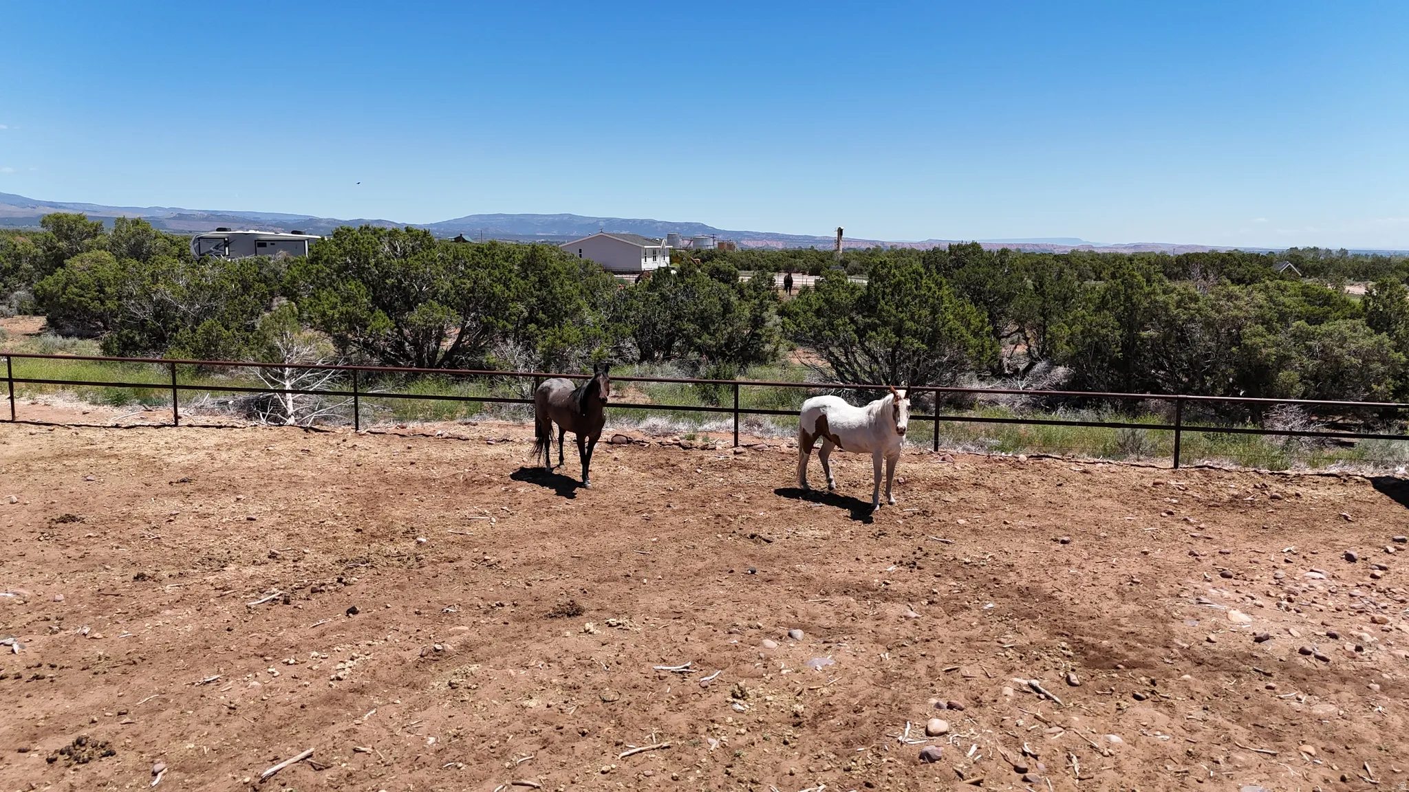 Fenced outdoor enclosure with open terrain and distant mountain range
