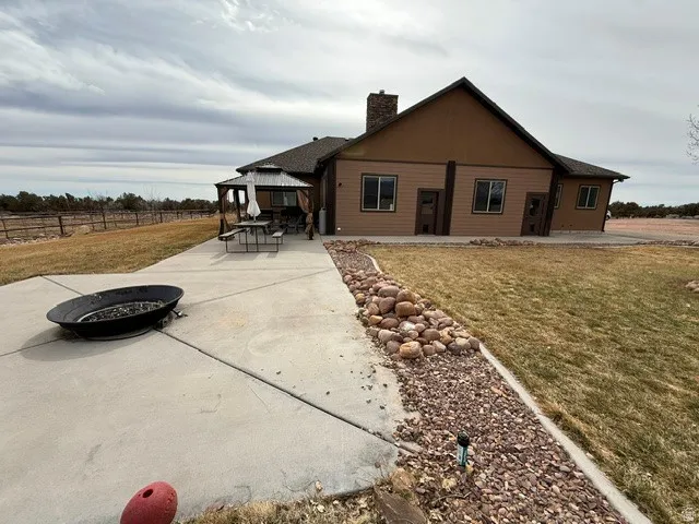 Back of property featuring a fire pit, a patio area, a gazebo, and a chimney