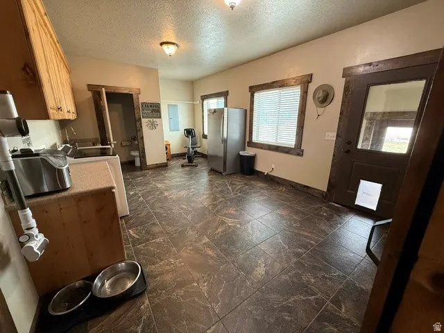 Kitchen with a textured ceiling, freestanding refrigerator, and white range oven