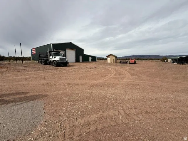 View of yard featuring an outdoor structure, a detached garage, a pole building, and driveway