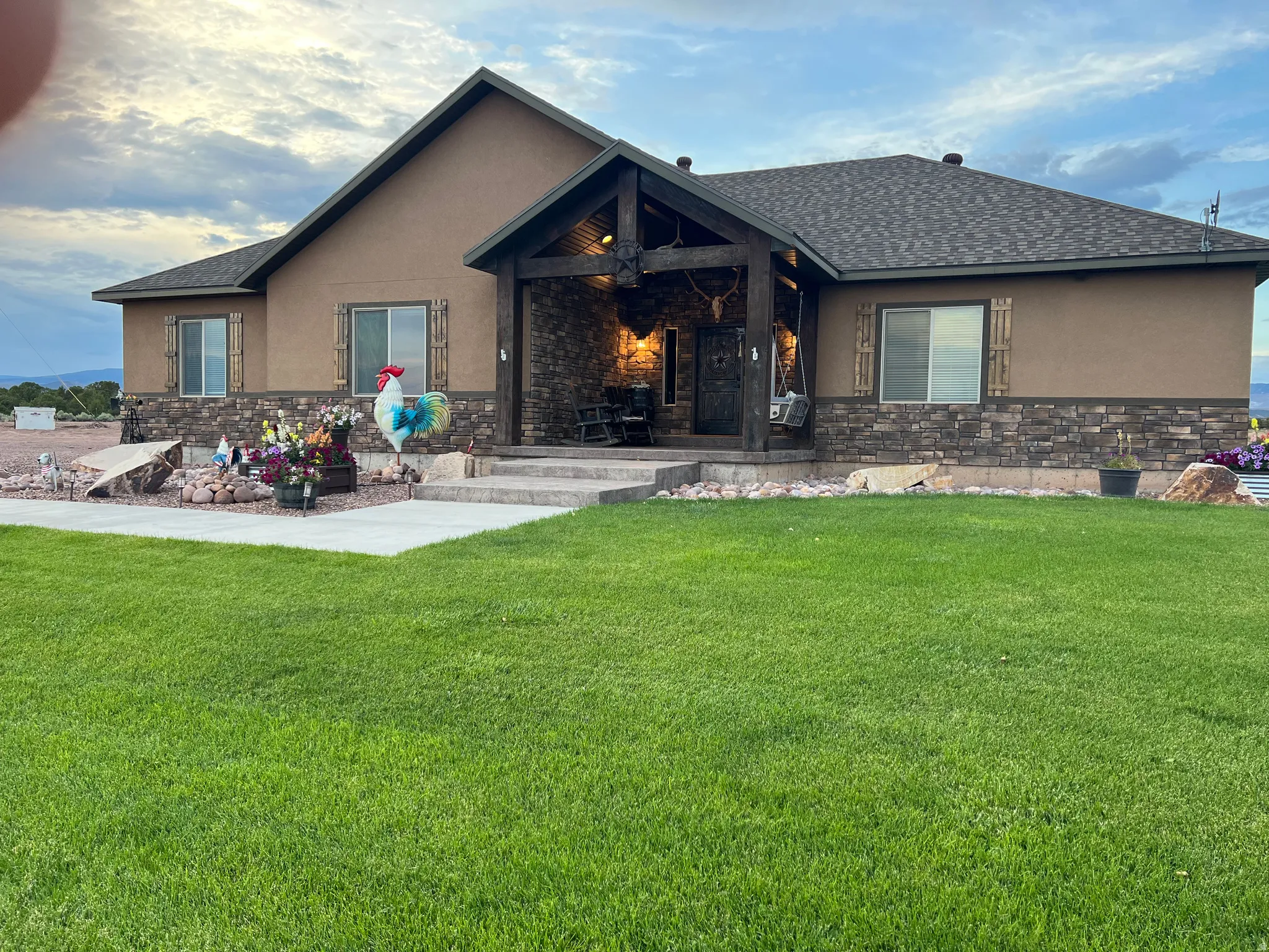 Stucco exterior with a stone veneer foundation and a covered entry porch featuring exposed timber beams
