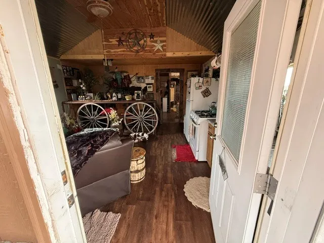Interior space with dark wood-style flooring, wooden walls, and a vaulted wooden ceiling