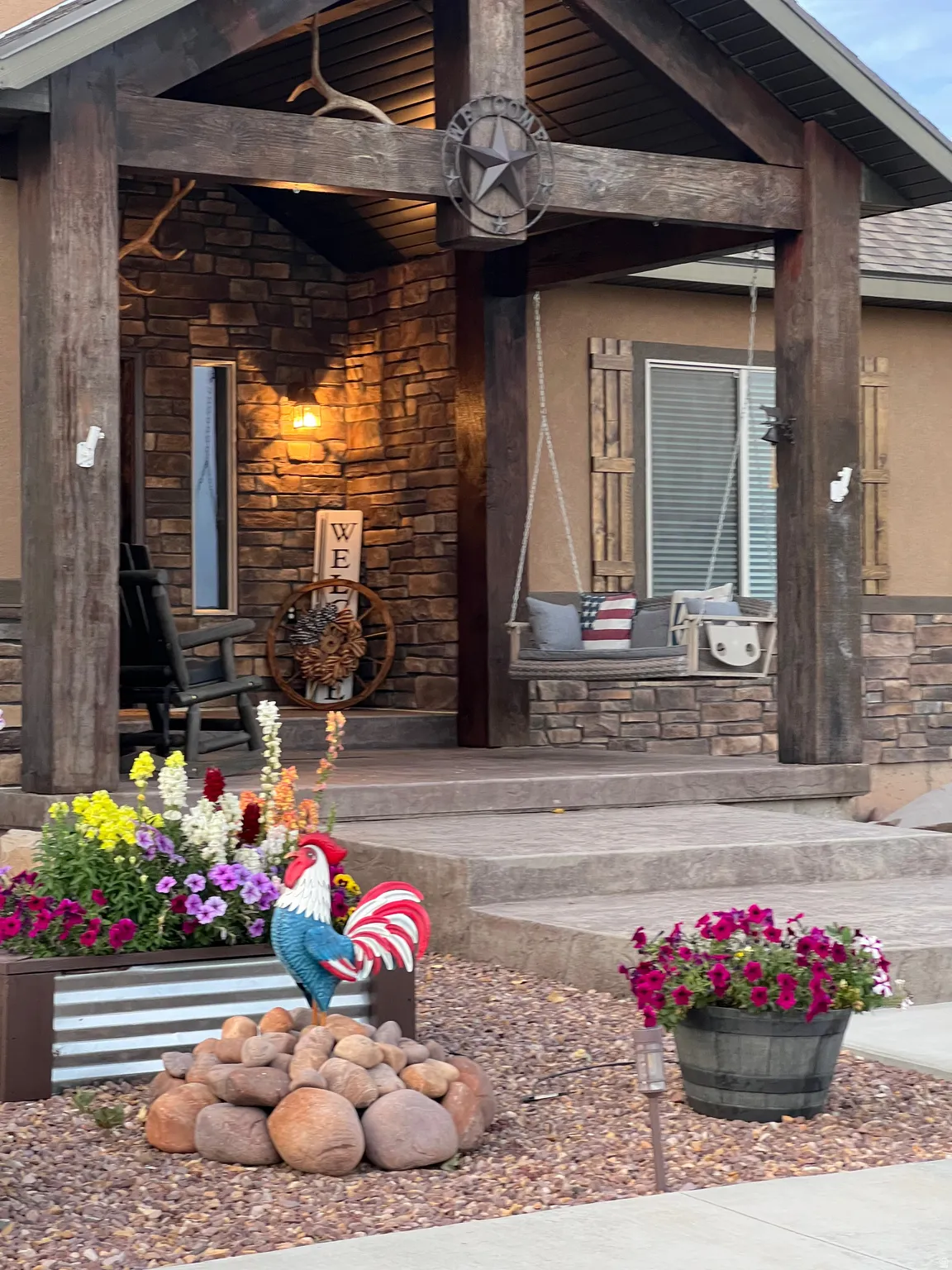 Stone facade entry featuring exposed wood beams, a porch swing, and a decorative light fixture