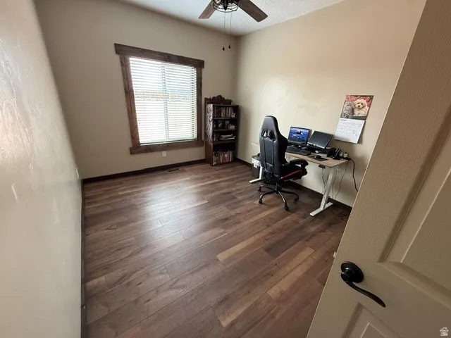 Home office featuring dark wood-type flooring and ceiling fan