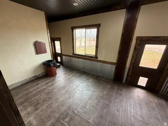 Unfurnished room with dark wood finished floors, a textured wall, and wooden ceiling