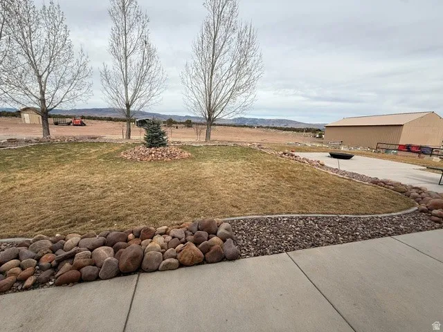 View of grassy yard with an outdoor structure and a mountain view