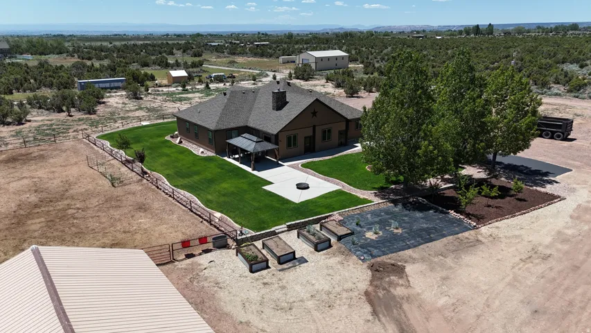 Expansive property featuring a brown-toned residence with a dark shingle roof, an attached covered patio, and a manicured green lawn