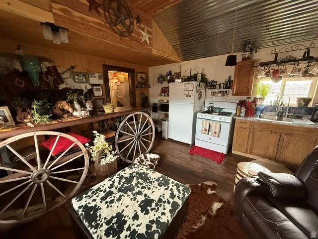 Kitchen with white appliances, dark wood-style flooring, wood finish cabinets, light countertops, and wood walls