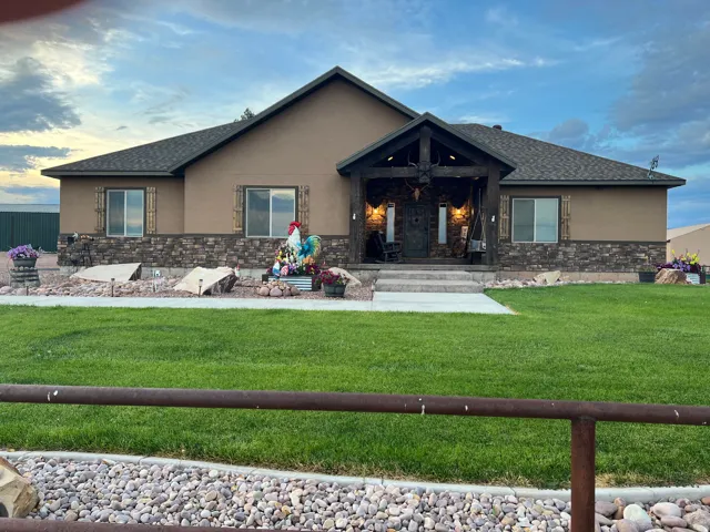 Exterior featuring a covered entry porch with exposed wood beams, stone veneer accents, stucco siding, and a gabled roofline