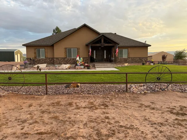 Single-story stucco residence with a prominent stone facade accent and dark shingle roofing