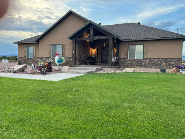 Stucco exterior with a stone veneer foundation and a covered entry porch featuring exposed timber beams